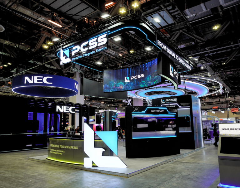 PCSS exhibition stand with illuminated overhead rings and product display counters at MTX 2026.